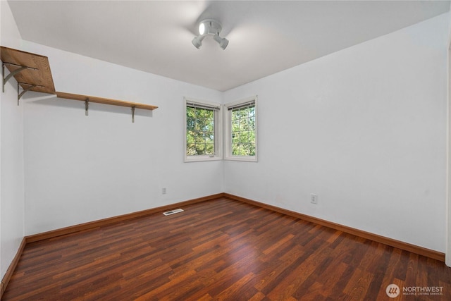 spare room featuring visible vents, baseboards, and wood finished floors