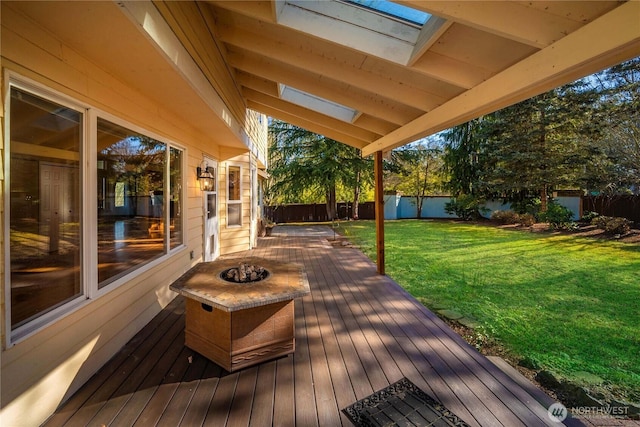 wooden deck featuring a fenced backyard, a fire pit, and a yard