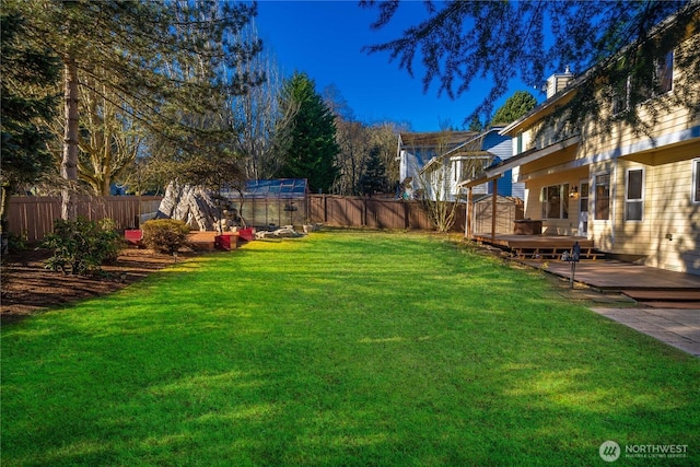 view of yard featuring a deck, an outdoor structure, and a fenced backyard