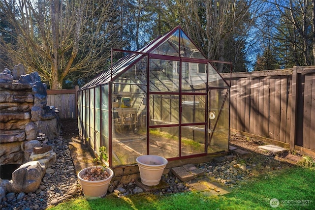 view of greenhouse with a fenced backyard