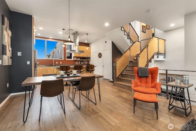 dining area with light wood-style floors, recessed lighting, baseboards, and stairs