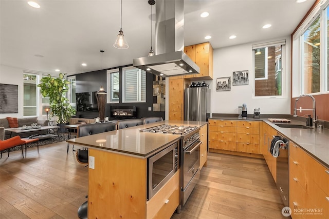 kitchen with a kitchen island, open floor plan, hanging light fixtures, island exhaust hood, and a sink