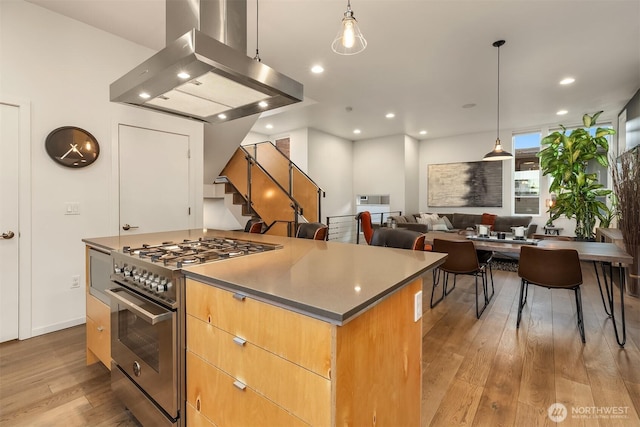 kitchen with stainless steel stove, a kitchen island, light wood finished floors, modern cabinets, and island exhaust hood