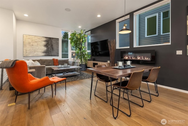 interior space with recessed lighting, baseboards, a glass covered fireplace, and light wood finished floors