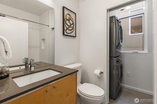 bathroom with stacked washer / dryer, vanity, and toilet