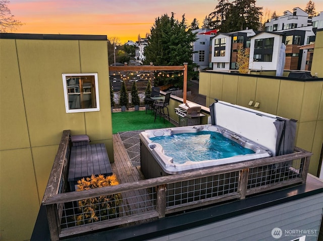 deck at dusk featuring a hot tub and a residential view