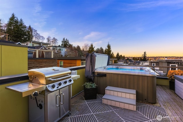 patio terrace at dusk featuring a wooden deck, a residential view, and a hot tub