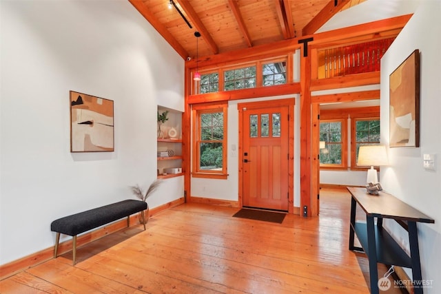 entryway with wood ceiling, light wood-style flooring, baseboards, and beam ceiling