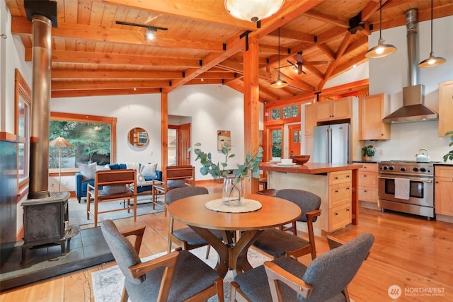 dining space with a wood stove, wooden ceiling, light wood-type flooring, and beamed ceiling