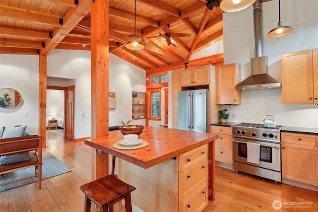 kitchen featuring wall chimney exhaust hood, wood counters, decorative light fixtures, stainless steel appliances, and light brown cabinetry