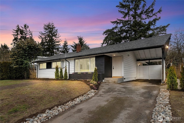 ranch-style house featuring a chimney, fence, concrete driveway, and brick siding