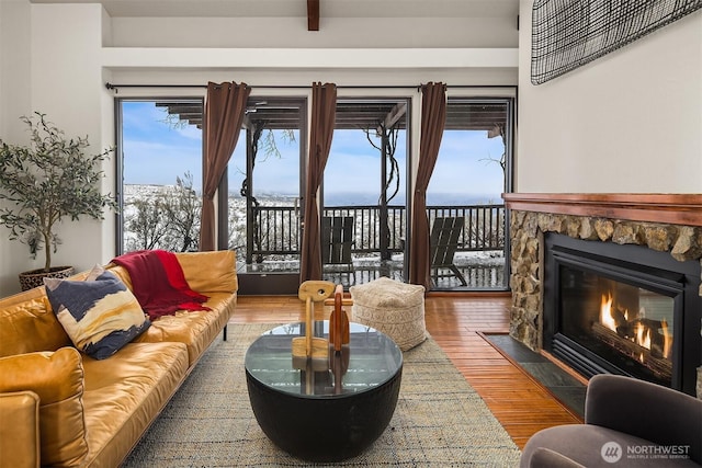 living room featuring a fireplace, wood finished floors, visible vents, and a water view