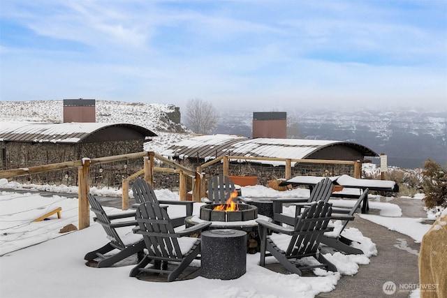 snow covered patio with an outdoor fire pit