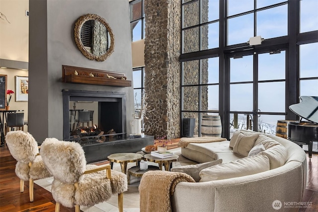 living area featuring a towering ceiling, a premium fireplace, and wood finished floors