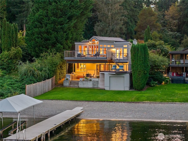 rear view of property featuring a lawn, metal roof, a balcony, and a standing seam roof