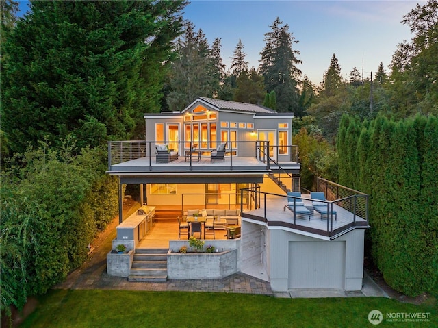 back of house at dusk with a wooden deck, stairway, outdoor lounge area, a balcony, and a forest view