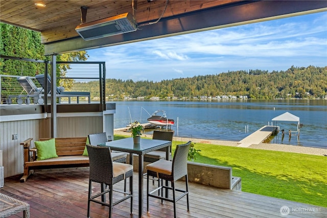 view of dock featuring a lawn, a water view, and a wooded view