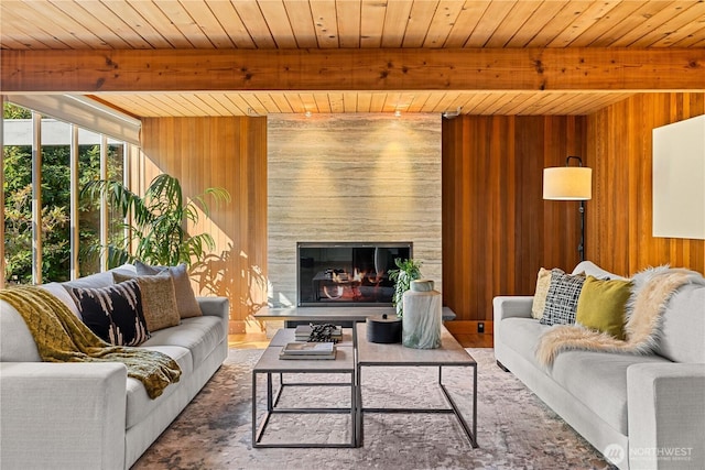 living room featuring a large fireplace, beamed ceiling, wood walls, and wooden ceiling