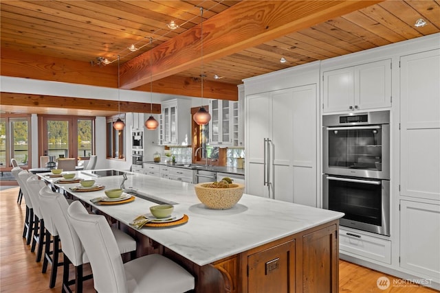 kitchen featuring glass insert cabinets, light wood-type flooring, white cabinets, wooden ceiling, and stainless steel appliances