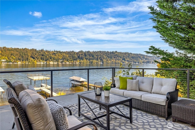 balcony featuring a view of trees, a water view, and an outdoor living space