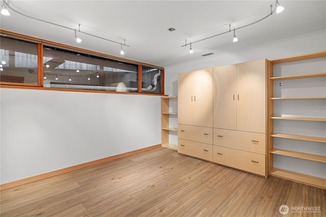 interior space featuring baseboards, rail lighting, wood finished floors, and visible vents