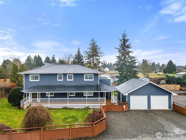 farmhouse-style home with an attached garage, driveway, an outdoor structure, and a front yard