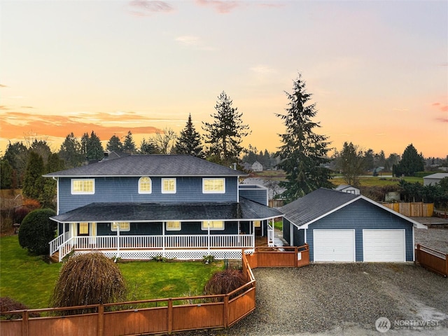 farmhouse-style home featuring an outbuilding, an attached garage, fence, driveway, and a lawn