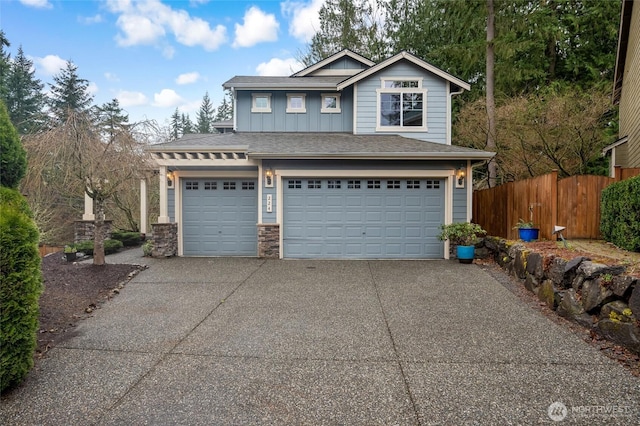 view of front of home with stone siding, board and batten siding, concrete driveway, and fence