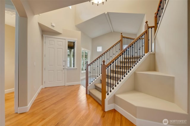 entryway featuring stairs, vaulted ceiling, wood finished floors, and baseboards