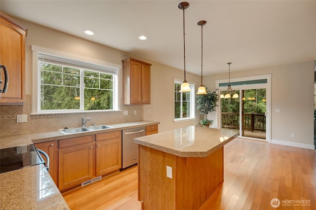 kitchen featuring tasteful backsplash, a sink, a kitchen island, light wood-style flooring, and stainless steel dishwasher