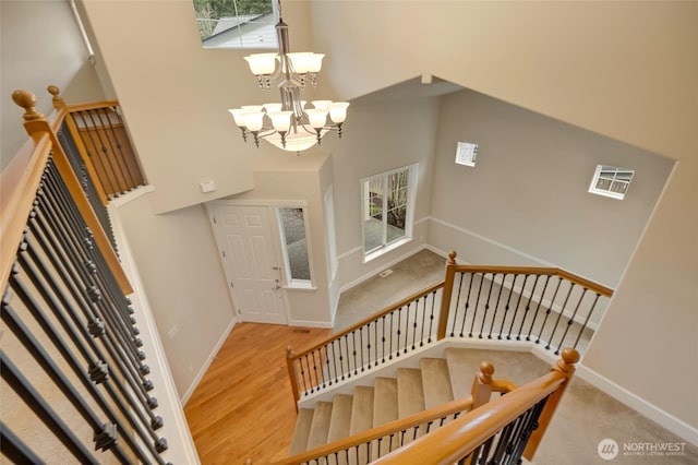 entryway featuring wood finished floors, baseboards, a towering ceiling, and a chandelier