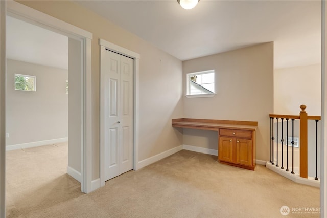 interior space featuring a wealth of natural light, baseboards, light carpet, and built in study area