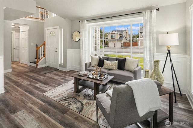 living room featuring a wainscoted wall, stairway, wood finished floors, and a decorative wall