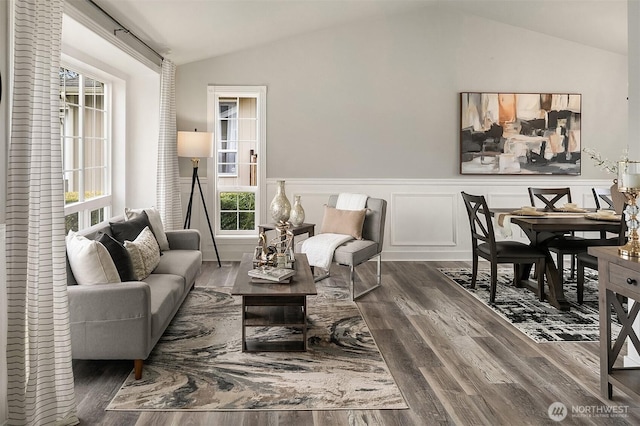 living room with dark wood-type flooring, lofted ceiling, and a wainscoted wall