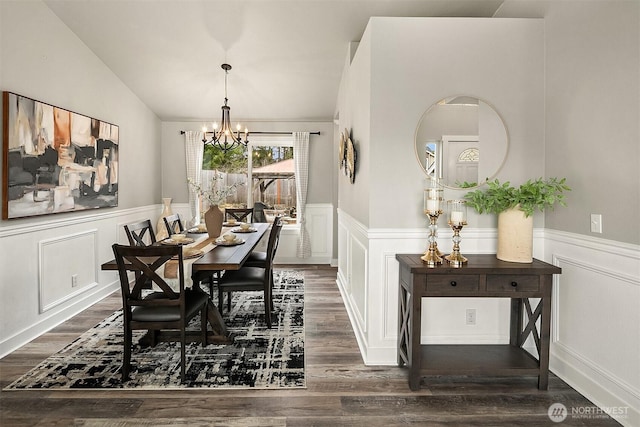 dining area with vaulted ceiling, dark wood finished floors, a notable chandelier, and wainscoting