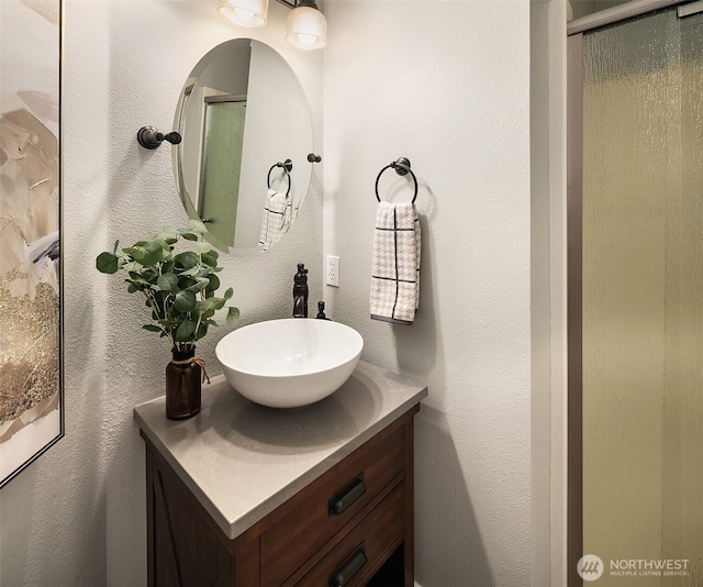 full bath featuring a textured wall, a stall shower, and vanity