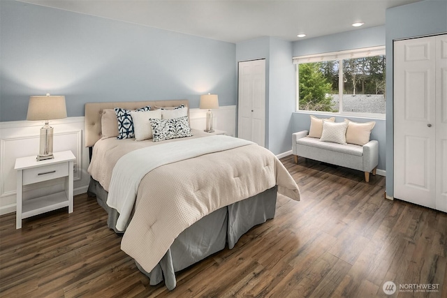 bedroom with dark wood-style floors, baseboards, and two closets