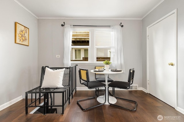 dining room featuring ornamental molding, dark wood finished floors, and baseboards