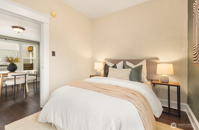 bedroom with dark wood-type flooring and baseboards