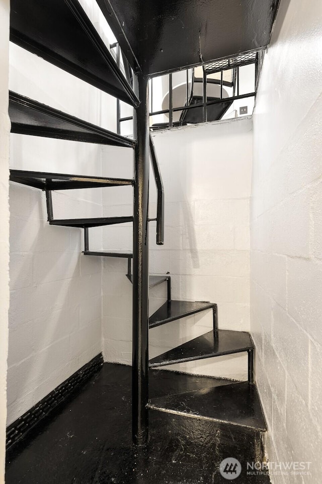 stairway featuring concrete block wall and concrete floors