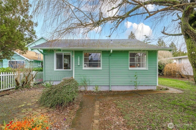 rear view of property featuring fence and a lawn