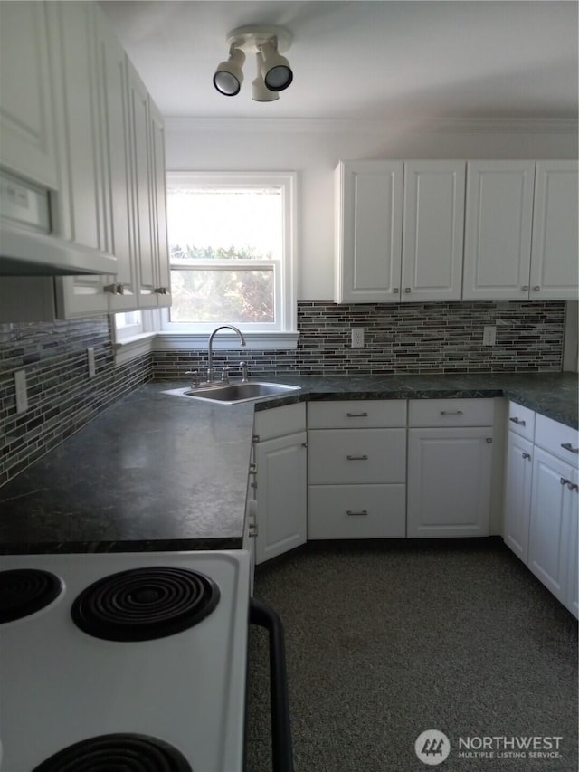 kitchen featuring backsplash, dark countertops, a sink, and white cabinetry