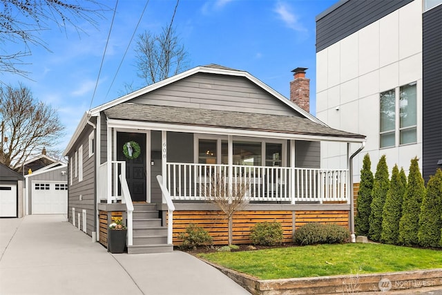 view of front of home with a front lawn, a porch, an outdoor structure, a shingled roof, and a chimney