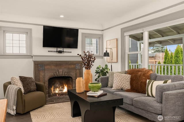 living room featuring a stone fireplace, recessed lighting, wood finished floors, and ornamental molding