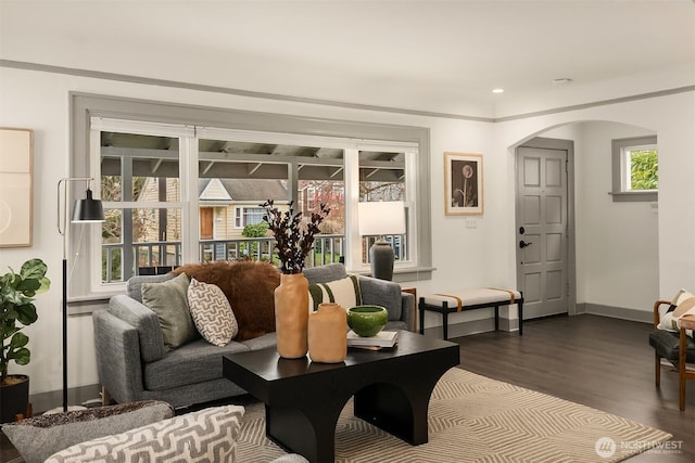 living room featuring recessed lighting, baseboards, arched walkways, and dark wood-type flooring