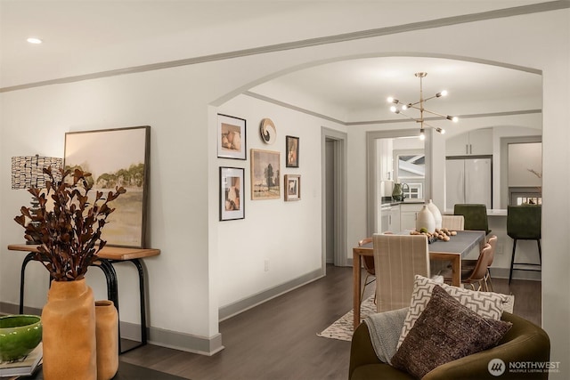 dining space with baseboards, dark wood-type flooring, arched walkways, and crown molding