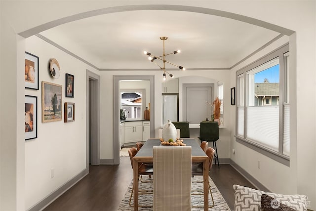 dining space featuring baseboards, arched walkways, dark wood-style flooring, crown molding, and a chandelier