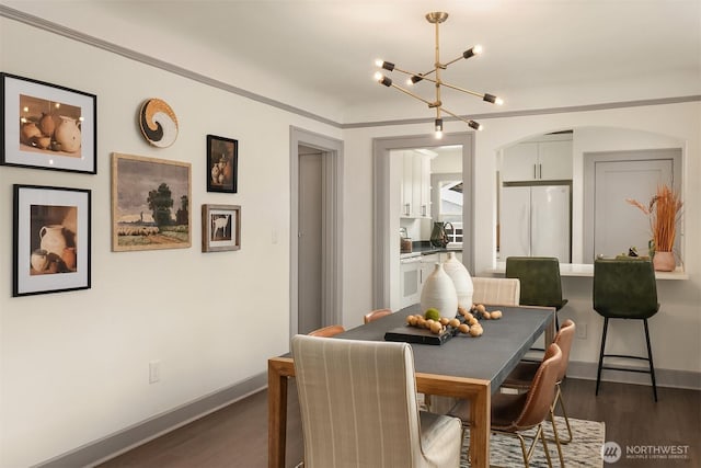 dining room featuring a chandelier, baseboards, arched walkways, and dark wood finished floors