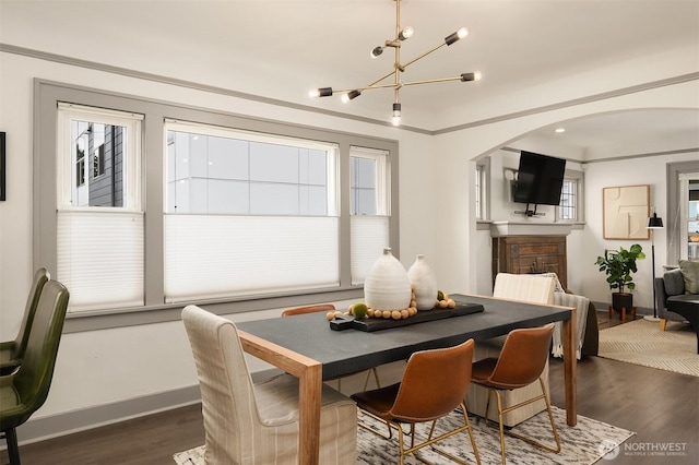 dining room featuring baseboards, arched walkways, dark wood-style floors, and crown molding