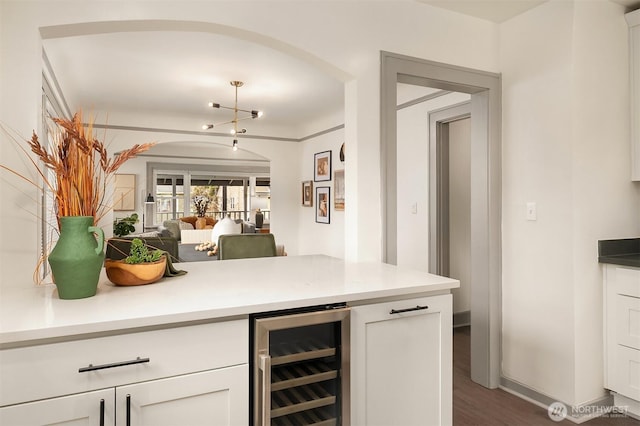 kitchen with dark wood-style floors, light countertops, wine cooler, white cabinetry, and open floor plan